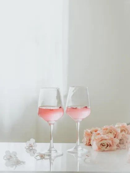 A minimalist and elegant shot of two glasses of rosé wine with pink roses. The bright, clean lighting and simple composition create a sophisticated and modern aesthetic.