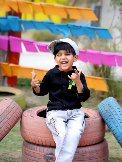A fun, high-energy shot of a boy playing on a stack of colorful tires in an outdoor play area.