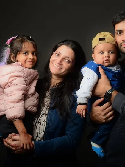 A full family portrait against a simple, dark background, which makes the subjects and their connection the main focus of the image.