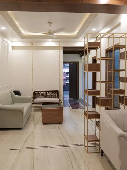 An open-plan living and dining area from a client's home, featuring a stunning gold and wood partition that adds style while defining the space.