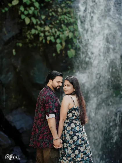 A beautiful portrait of a couple holding hands in front of a waterfall, with the bride looking back at the camera.