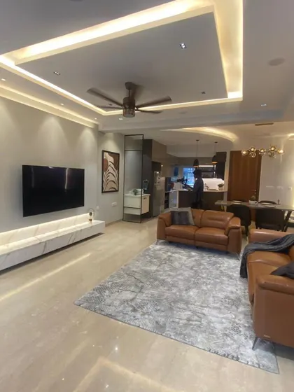 This shot shows the living room from another angle, emphasizing the spaciousness and the clean, modern design of the TV unit and false ceiling.