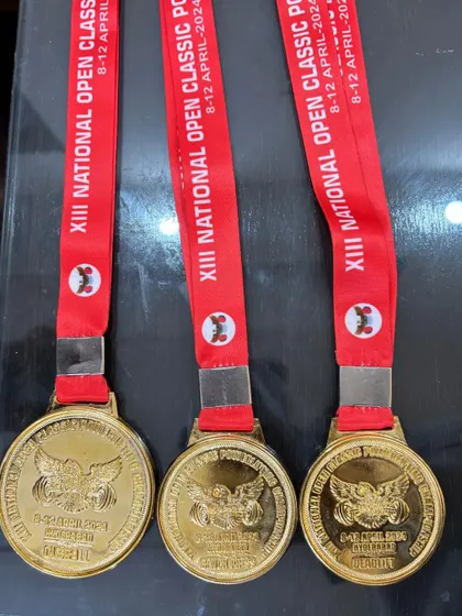 A close-up of the three gold medals I won at the National Classic Championship for bench press, deadlift, and the overall title.