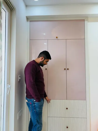 A custom wardrobe designed for a room in ATS Nobility. This piece features a beautiful combination of blush pink high-gloss laminate on the top and a textured white finish on the lower drawers.