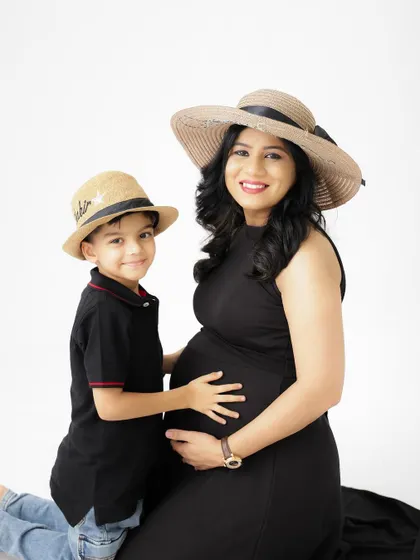 A sweet portrait of a mother and her son. They wear matching hats, and the son looks up at his mom with so much love and excitement for his new sibling.