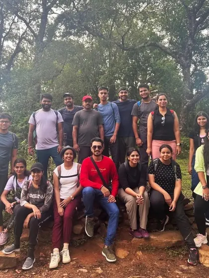 A team takes a break on the trail during the Netravati Peak trek, surrounded by the lush forest.