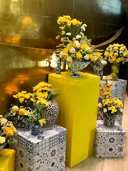 An elegant floral corner for a Haldi event, using yellow flowers and blue-and-white pottery for a unique touch.