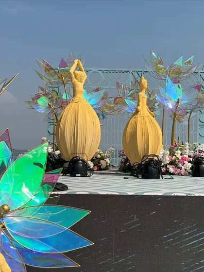The 'Dancing Dolls' stage during the day, showcasing the sculptural details and the iridescent lotus flowers against the sea view.