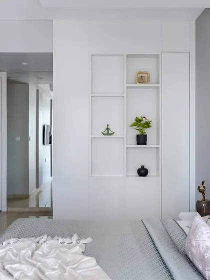 A wider view of the master bedroom with the backlit marble wall, showing the integrated shelving and the serene, sophisticated ambiance it creates.