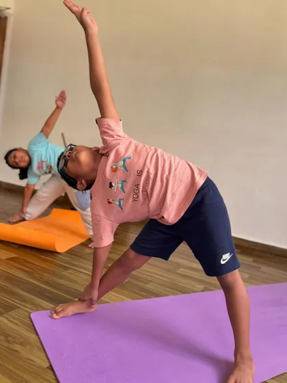 Two boys practicing Trikonasana, or Triangle Pose. This pose is excellent for stretching the sides of the body and strengthening the legs.