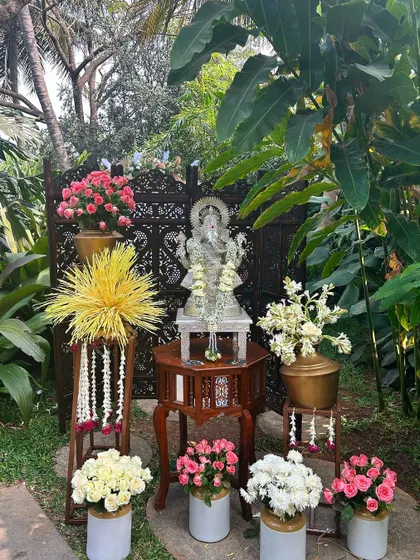 A sacred corner for blessings, featuring a silver Ganesha idol, traditional flower arrangements, and carved wooden screens.