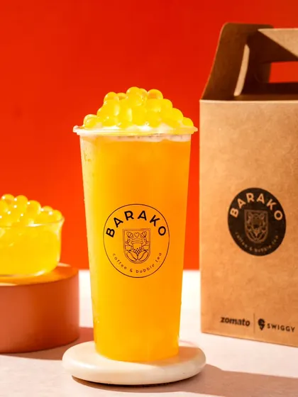 A bright mango bubble tea from Barako. The clean, monochromatic orange background makes the product colour pop.