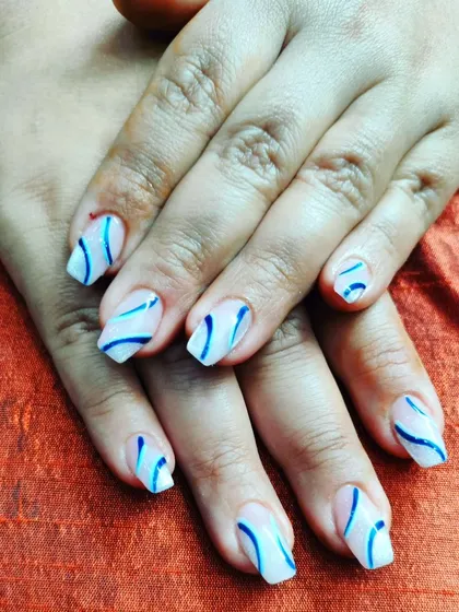 A simple yet stylish design with abstract blue swirls on a clean white base, done on short, natural nails.