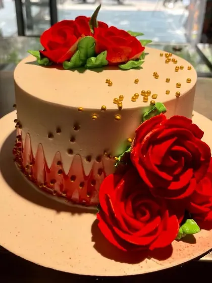 A simple yet stunning cake adorned with vibrant, handcrafted red sugar roses. The sprinkle of gold beads adds a touch of elegance to this classic design.