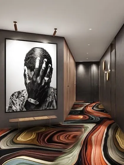 A hotel corridor with a bold, artistic design. The custom-designed carpet and large-scale artwork create a memorable and unique experience for guests.