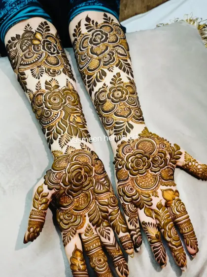 A beautiful and intricate floral design for a bride, with bold roses on the palms and detailed patterns on the arms.