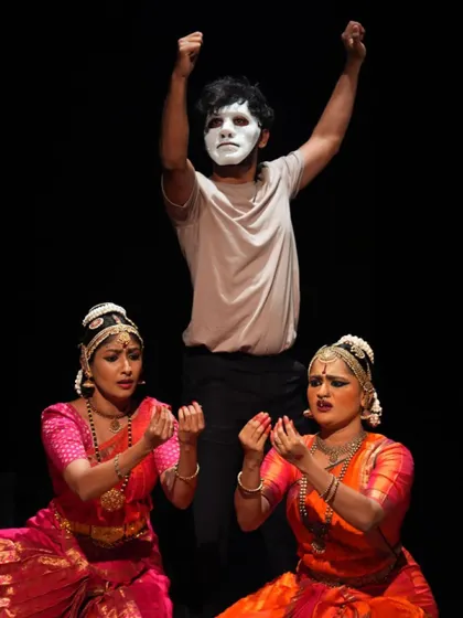A powerful tableau from "TATSAMA TADBHAVA," showing a masked figure with arms raised above two expressive Bharatanatyam dancers. This composition captures the production's dramatic storytelling.
