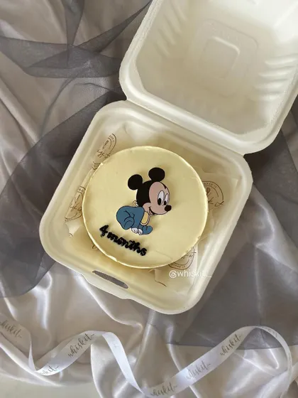 This bento cake features a hand-drawn baby Mickey Mouse to celebrate a 4-month milestone. It's a sweet way to mark those precious early months with a cute, personalized treat.