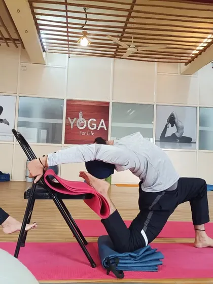A student practices a supported backbend using a chair. This demonstrates how props can be used to work towards more advanced poses like Kapotasana (Pigeon Pose) safely and effectively.
