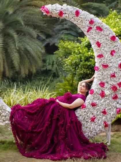 Resting on the floral moon, this mom-to-be looks serene and majestic in her deep purple gown.