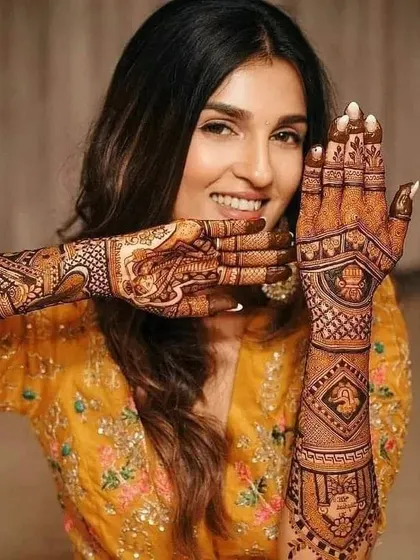 A beautiful bride showing off her intricate henna design. The patterns are a mix of traditional motifs and personalized elements.