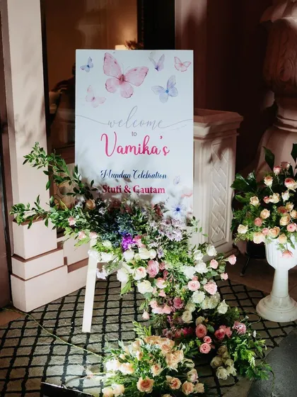 A beautiful floral welcome board for a naming celebration. The sign is adorned with a cascade of fresh flowers, creating an elegant and high-end look for the event entrance.