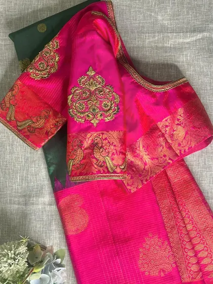 A vibrant pink Kanjeevaram saree blouse featuring a traditional woven border on the sleeve, which we have enhanced with a custom-embroidered zardosi motif.