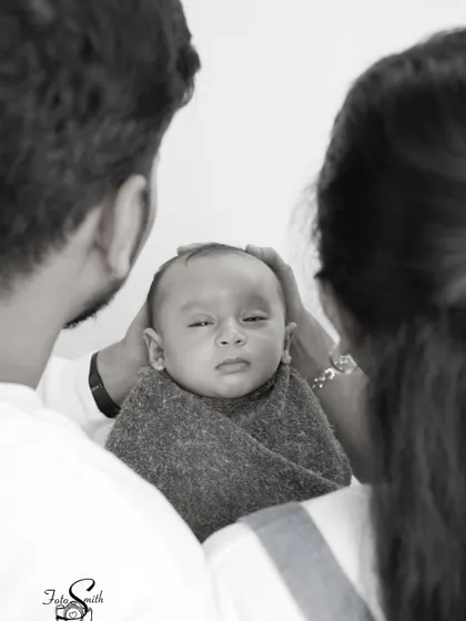 A unique perspective, looking over the parents' shoulders as they gaze at their newborn. This black and white shot feels intimate and protective.