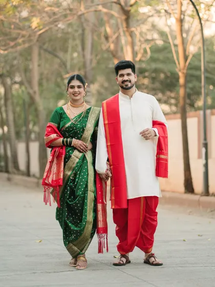 A full-length portrait of a couple in stunning Maharashtrian wedding attire, including the traditional dhoti and Nauvari saree, captured during a serene outdoor walk.