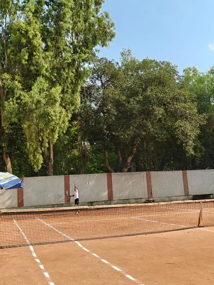 A wide shot of a player serving on our clay court. This view shows the full court, giving a sense of the space and environment where we train our athletes.