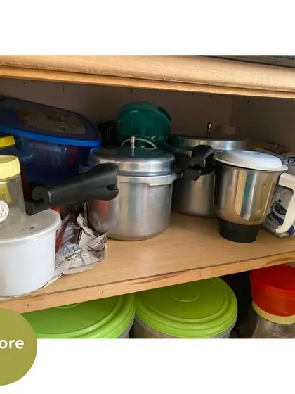 A cluttered under-cabinet space with pressure cookers, mixers, and other items piled on top of each other.