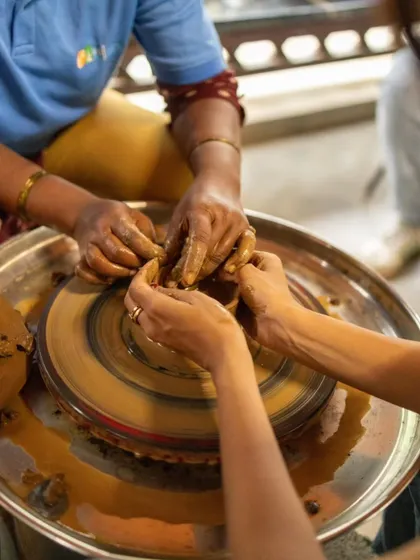 Our instructor provides hands-on guidance, helping a guest feel the rhythm of the wheel and the movement of the clay.