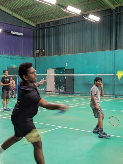 A coach demonstrates the proper form for a shot while a junior player observes. Our sessions involve a mix of active drills and direct instruction.