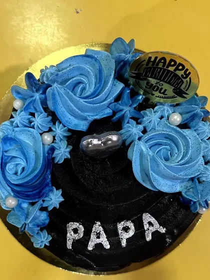 A special cake for "Papa" in a striking black and blue design. The rich black frosting is contrasted with bright blue piped rosettes and a "Happy Birthday to You" topper.