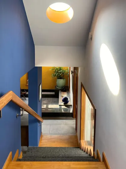 Sunlight streams down a staircase, casting a bright oval on the wall. We carefully plan the placement and shape of skylights to create these beautiful, fleeting moments of light and shadow.