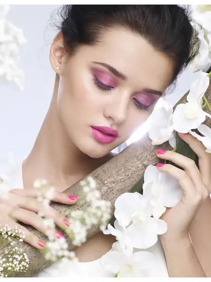 A soft and romantic beauty image featuring floral elements and vibrant pink makeup. The composition creates a dreamy, ethereal mood, perfect for a spring cosmetics collection.