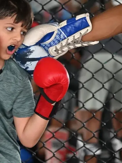 A young student practicing his boxing defense, slipping a punch from his coach. We teach both offense and defense from the very beginning.