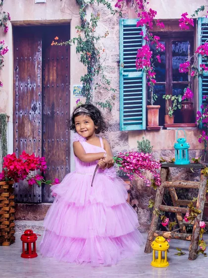 A little princess in a tiered lavender gown, posing in a beautiful floral setting. The soft colors and her sweet smile make this a dreamy and elegant child portrait.