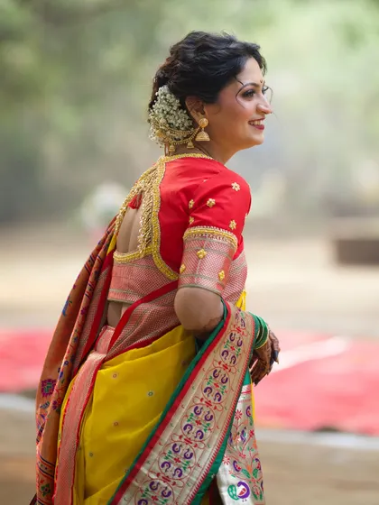 A beautiful back profile showcasing the intricate hairstyle and blouse design. The classic bun adorned with a fresh flower gajra is a hallmark of traditional bridal beauty.