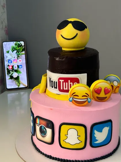 A fun, two-tier cake for a digital marketing company's anniversary. The design is covered in social media logos and popular emojis, all handcrafted from fondant.
