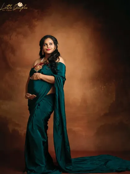 A fine art portrait with a dramatic, painterly background. The deep green of the saree stands out beautifully, creating a rich and elegant image.