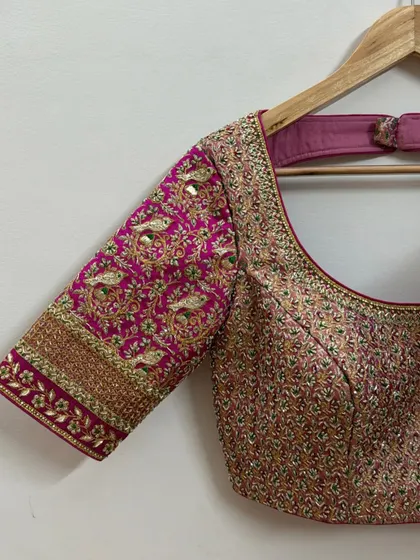 Another angle of the peacock motif blouse, showing the detailed craftsmanship and the shimmer of the zardosi work against the rich pink silk fabric.