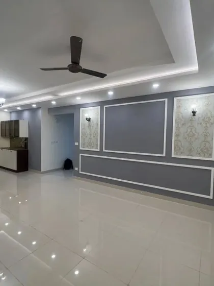 An unfurnished living room showing the completed wall treatments and ceiling design. The grey accent wall with white moulding and classic sconces creates an elegant backdrop for any furniture style.