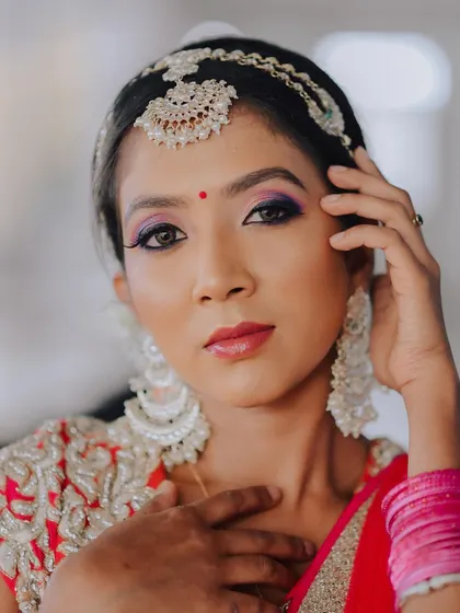 A confident and direct portrait. The close framing captures the details of her makeup, jewelry, and the intensity of her expression.