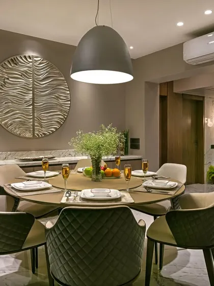 This intimate dining nook is perfect for family meals. A large pendant light anchors the round table, while quilted chairs and a textured wall art piece add layers of comfort and sophistication.