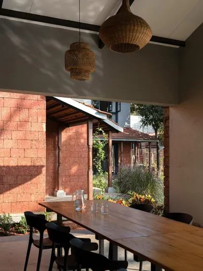 The outdoor dining area at Maison Rouge, sheltered by a deep veranda supported by reclaimed timber columns. This space is perfect for enjoying meals while immersed in the sights and sounds of the countryside.