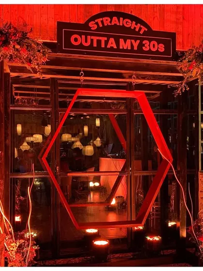 Milestone birthdays deserve a grand entrance. I designed this 'Straight Outta My 30s' entryway with dramatic red lighting, a custom sign, and a geometric swing installation that served as the perfect photo opportunity for the guest of honor and their friends.