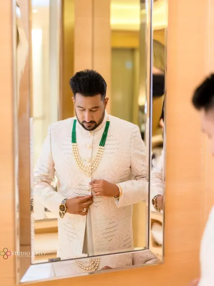 A classic shot of the groom getting ready, adjusting his outfit in the mirror.