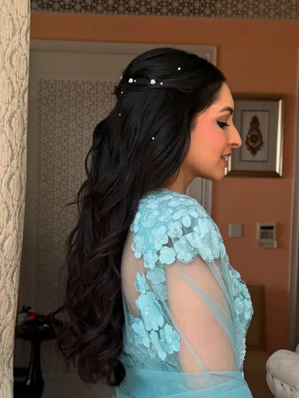 A side view of the pearl-dotted half-up style, showing the soft waves and elegant twist.
