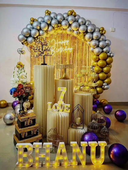 A surprise birthday decoration with gold and silver balloons, a fringe curtain, and various props to make the occasion special.